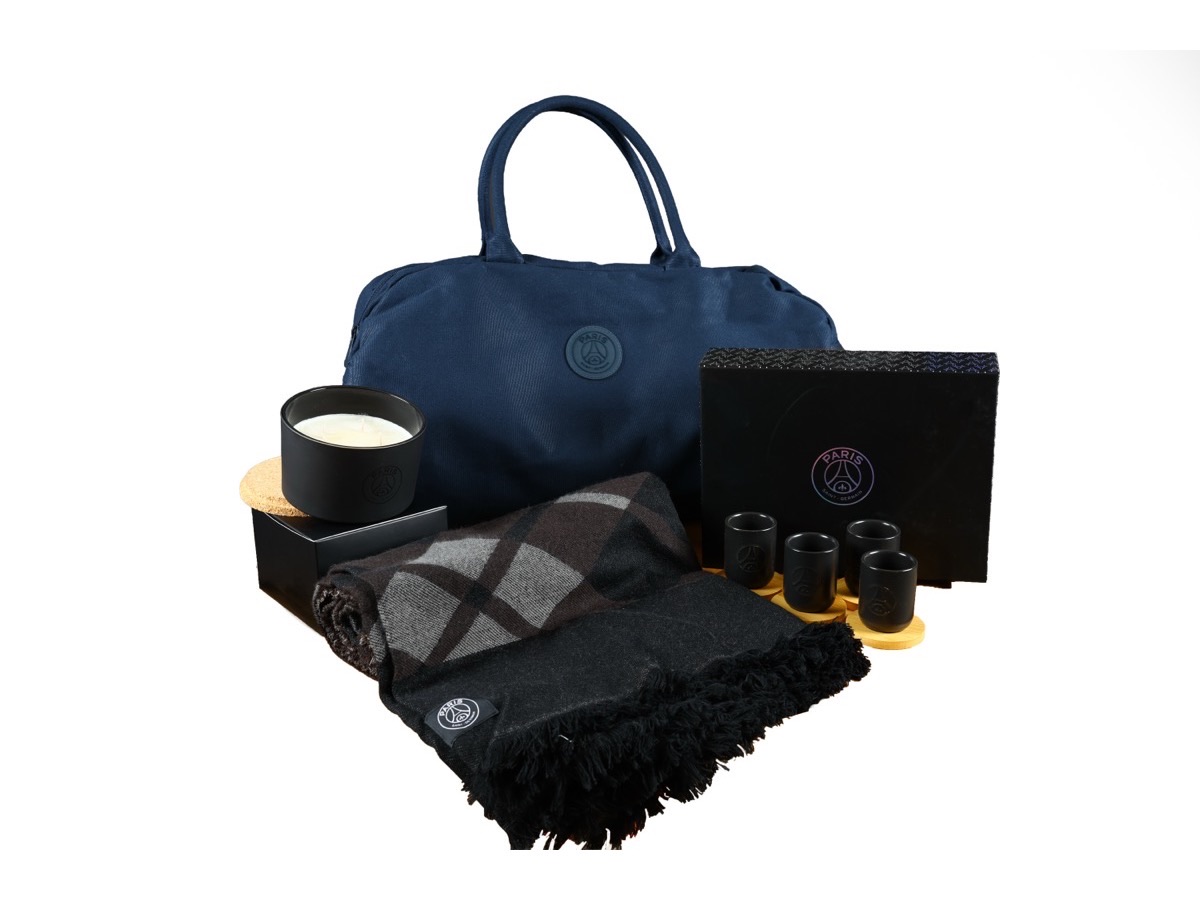 Set de goodies officiels PSG : sac, bougie, plaid et accessoires aux couleurs du club, sur fond blanc